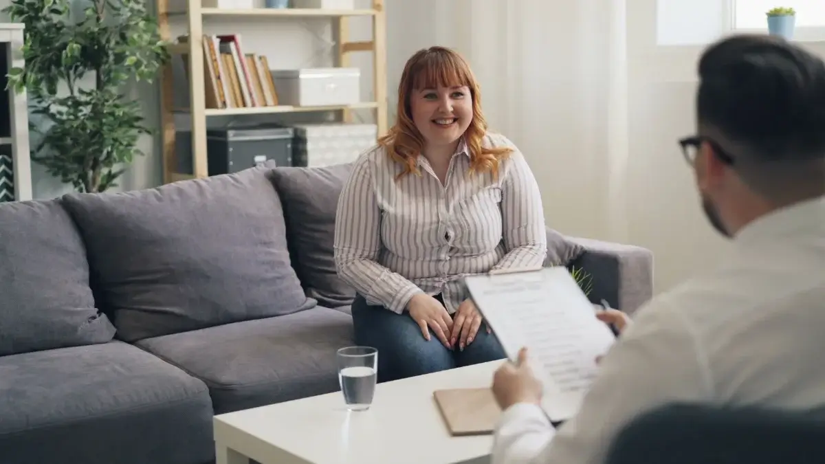 Smiling client talking with a therapist on a sofa during a CBT session